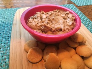 Close up of a chunky yet smooth dip that is a tannish color. This is Pecan Praline Dip. It's served with vanilla wafers.