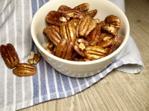 Sweet, spicy, salty candied pecans in a white bowl on a table.