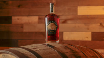 A bottle of Wicked Harvest Pecan Bourbon Whiskey sits on a barrel.