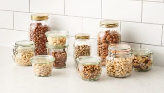 A variety of tree nuts in different glass jars.