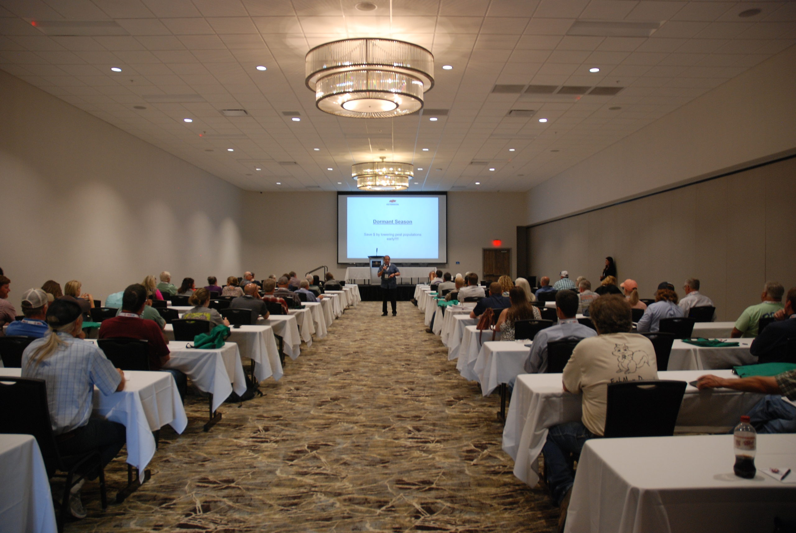 A man presents to a crowd of seated people at a conference.