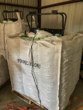 Floor fans set on top of supersacks and blow air into super sacks full of inshell pecans in order to dry the nuts and maintain quality.