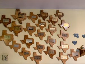 Numerous wooden Texas-shaped plaques hang on a wall in Mr. Schuetze's home.