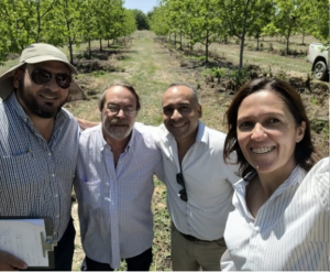 A group of four people pose for a selfie in an high-density orchard in Argentina.