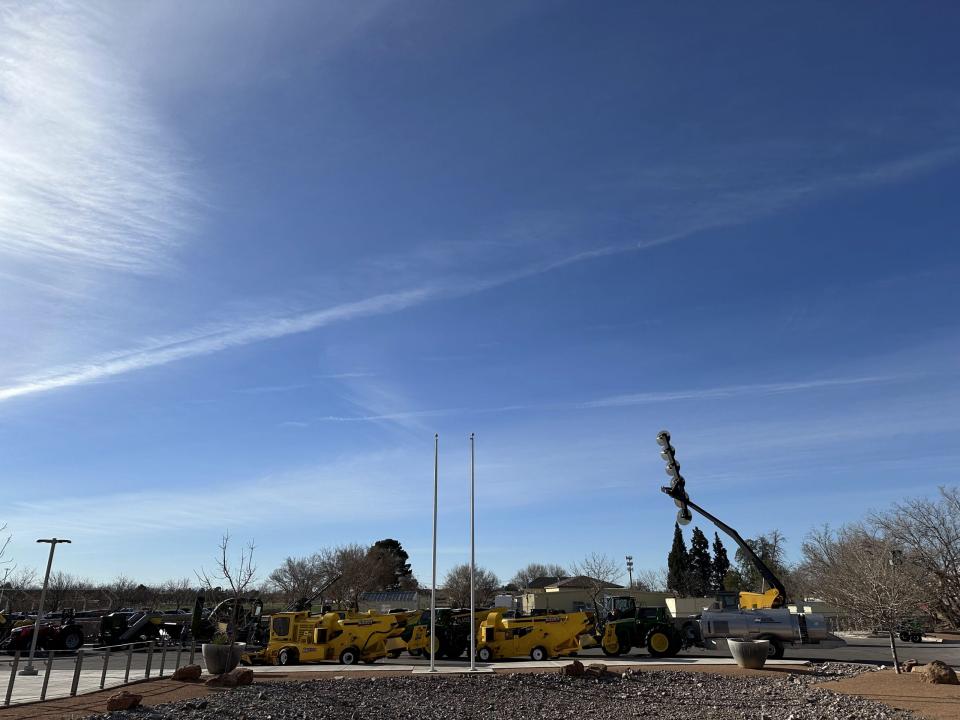 Pecan equipment lined up in a row outside the conference center and backdropped by a  bright blue sky.
